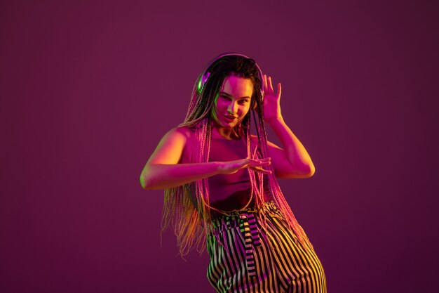 Portrait of young woman on pink wall with headphones