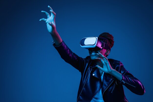 Portrait of young woman playing in VR-glasses in neon light