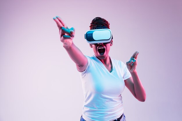 ネオンの光の中でVRメガネで遊ぶ若い女性の肖像画