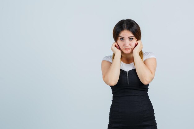 Portrait of young woman plugging ears with fingers and looking scared