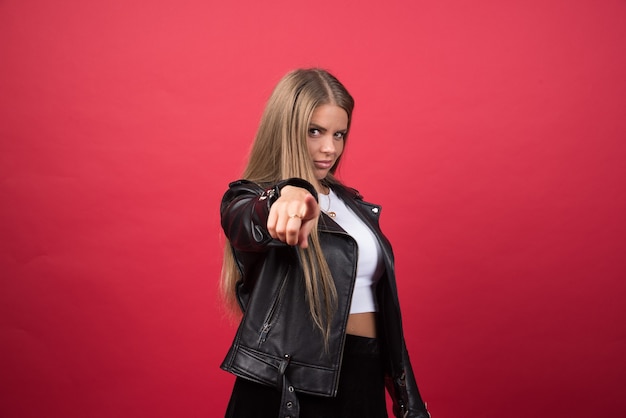 Free photo portrait of a young woman pointing at a camera with a finger