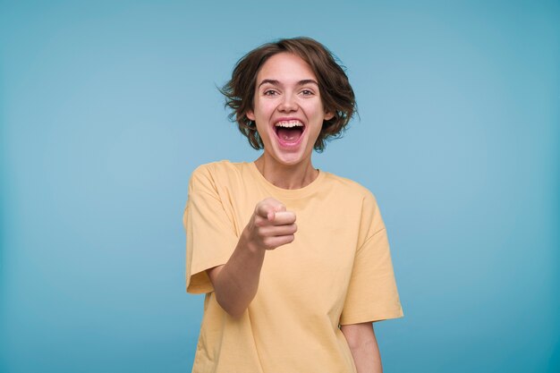Portrait of a young woman pointing at something and laughing