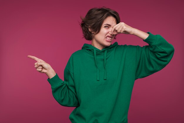 Portrait of a young woman pointing at something that smells bad