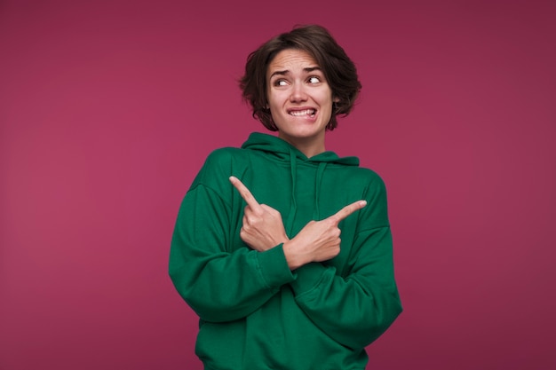 Portrait of a young woman pointing in two directions