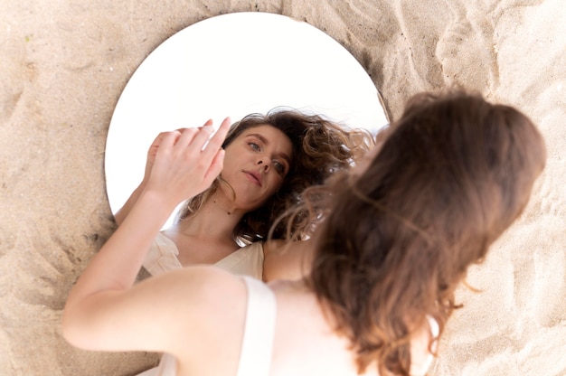 Free photo portrait of young woman posing confidently outdoors with a round mirror