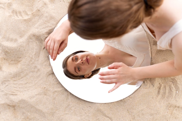 Free photo portrait of young woman posing confidently outdoors with a round mirror