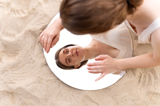 Portrait of young woman posing confidently outdoors with a round mirror