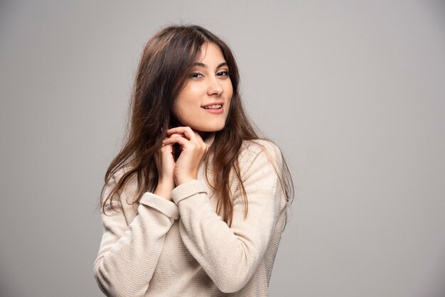 Portrait of a young woman posing on a gray wall .