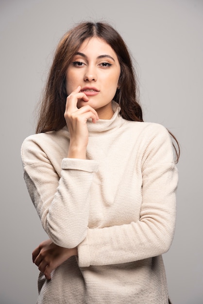 Portrait of a young woman posing on a gray wall .