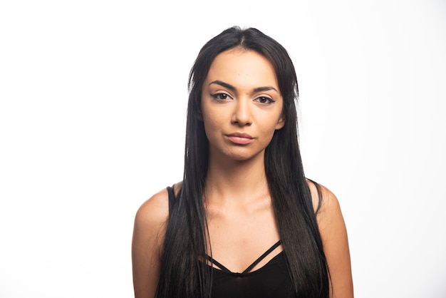 Portrait of young woman posing on white wall