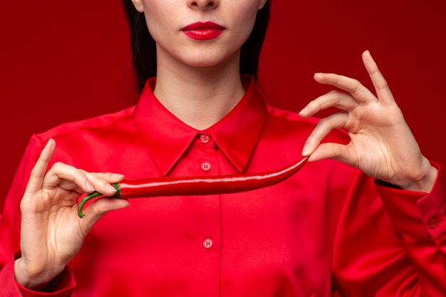 Portrait of young woman posing with chili pepper