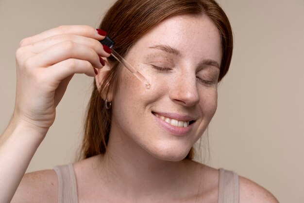 Portrait of a young woman pouring serum on her face