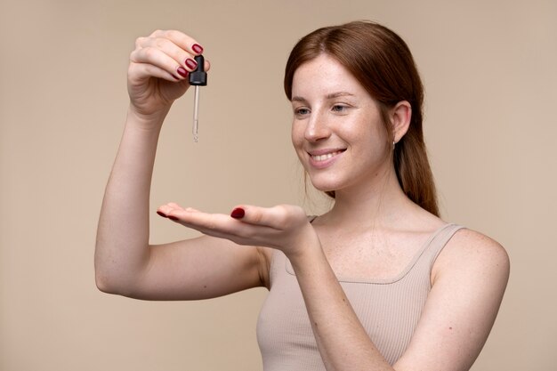 Portrait of a young woman pouring serum on her hand