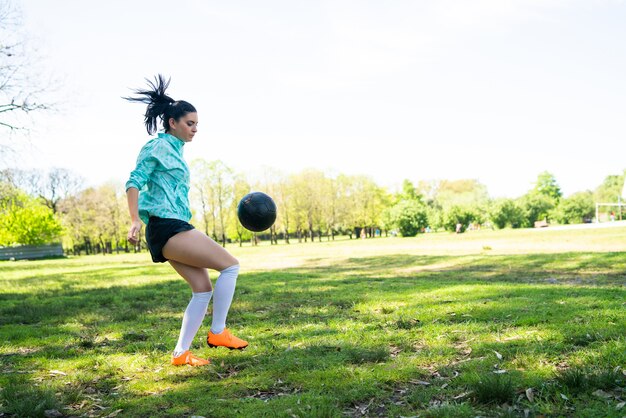 Portrait of young woman practicing soccer skills and doing tricks with the football ball