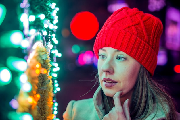 Ritratto della giovane donna nel cappello rosso lavorato a maglia. felicità, vacanze invernali, natale e persone concetto - sorridente giovane donna in cappello rosso