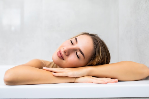 Portrait of young woman relaxing in bathtub at home