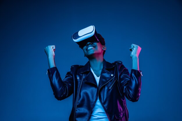 Portrait of young woman's playing in VR-glasses in neon light on blue