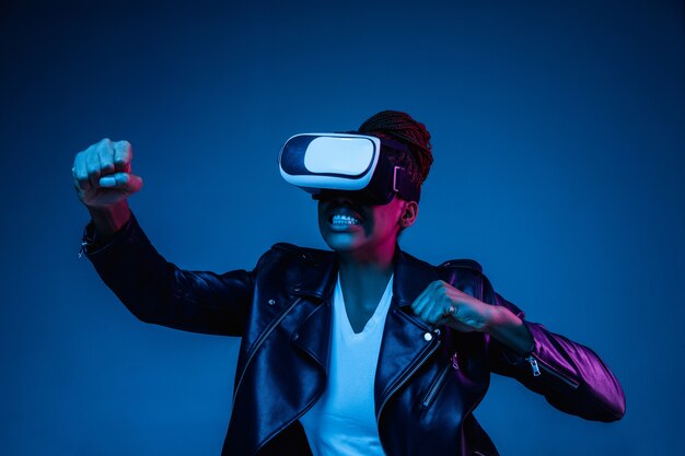 Portrait of young woman's playing in VR-glasses in neon light on blue