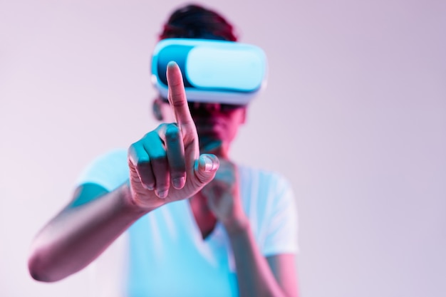 Портрет молодой женщины, играющей в VR-очках в неоновом свете на градиенте