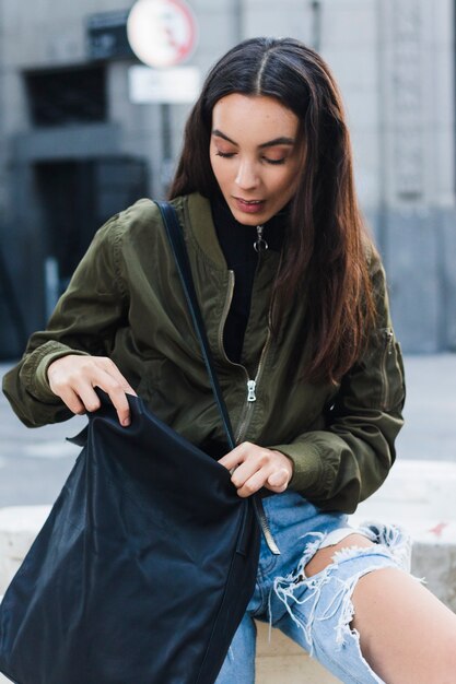 Portrait of a young woman searching in her bag