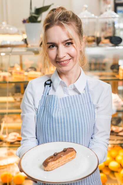 Portrait of a young woman serving the slice of chocolate cake