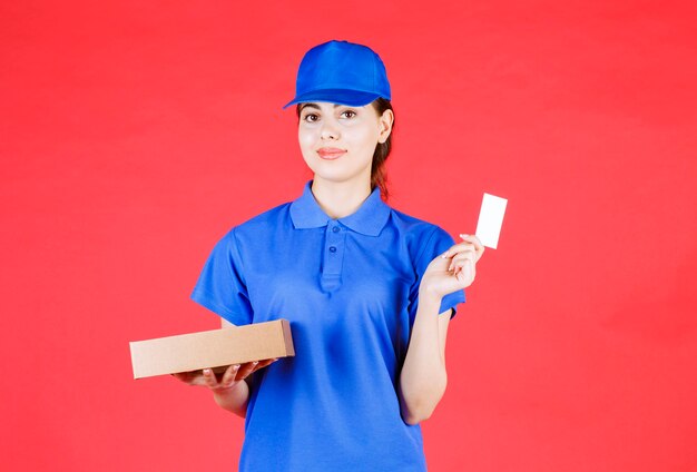 Portrait of young woman showing business card and holding carton box.