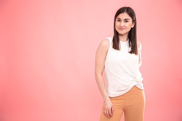 Portrait of a young woman showing emotions on an isolated pink background.