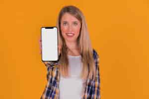 Foto gratuita ritratto di una giovane donna che mostra il suo telefono cellulare su sfondo arancione