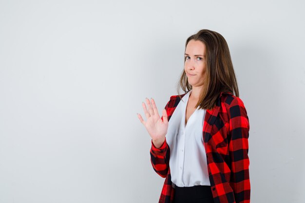 Portrait of young woman showing stop gesture in casual clothes and looking bored front view