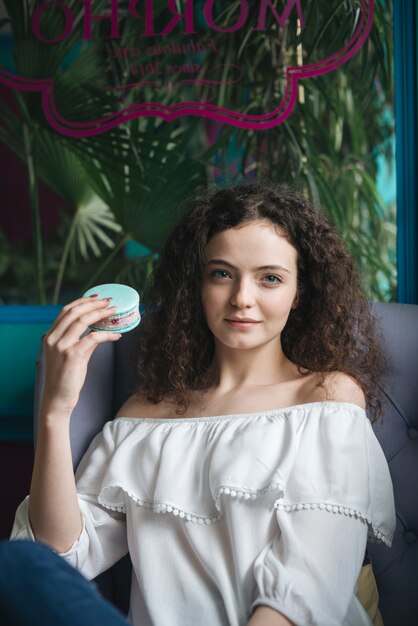 アイスクリームサンドイッチを保持しているカフェに座っている若い女性の肖像画