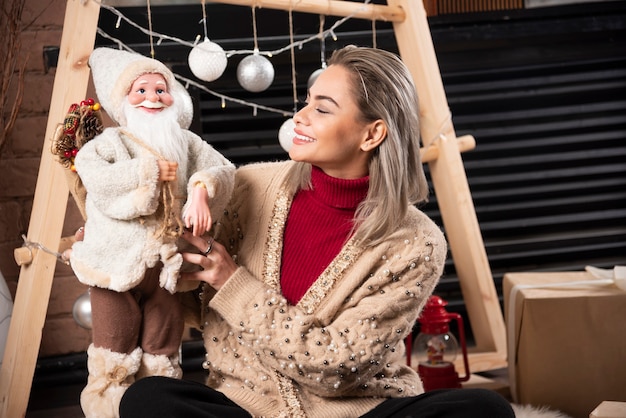 Portrait of young woman sitting and posing with a Santa Claus toy.High quality photo