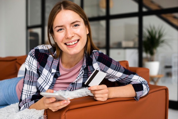 Free photo portrait of young woman sitting on sofa with phone