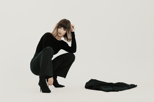 Portrait young woman sitting with attitude on white