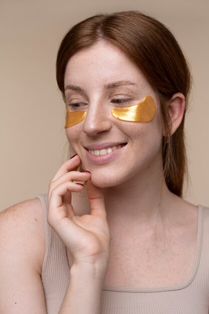 Portrait of a young woman smiling and wearing under-eye patches