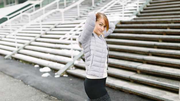 Portrait of a young woman standing in front of bleachers