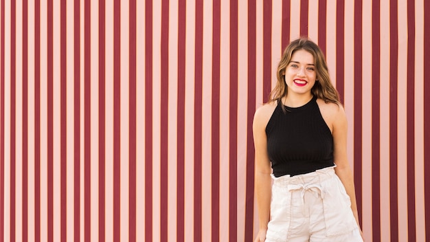 Free photo portrait of young woman standing in front of wallpaper