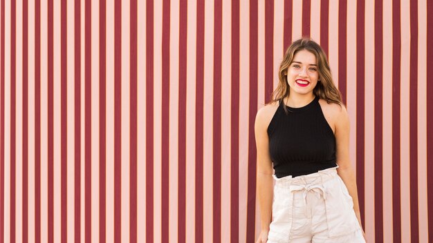 Portrait of young woman standing in front of wallpaper