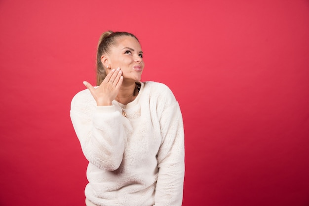 Portrait of a young woman standing and posing on a red wall