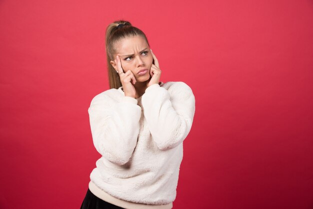 Portrait of a young woman standing and posing on a red wall