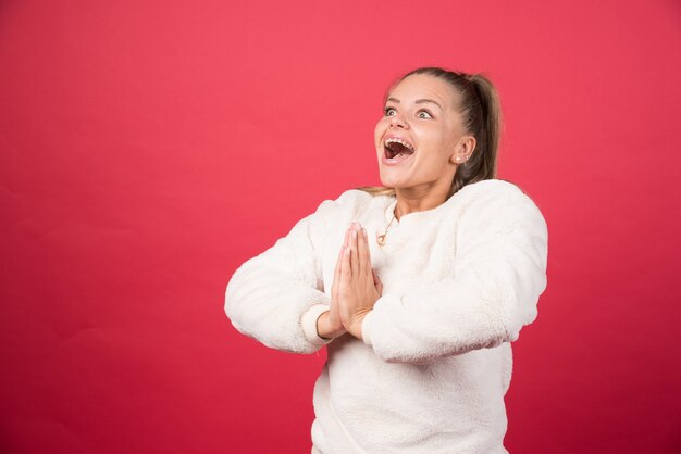 Portrait of a young woman standing and posing on a red wall