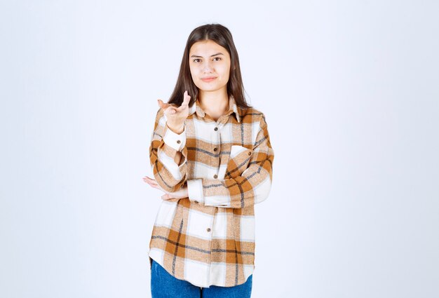 Portrait of young woman standing and posing on white wall. 