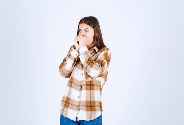 Portrait of young woman standing and posing on white wall. 