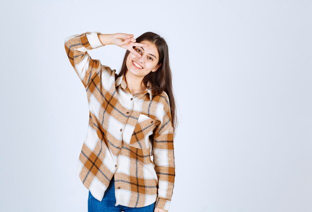 Portrait of young woman standing and smiling to camera over white wall. 