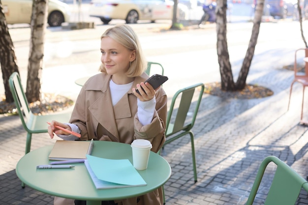 portrait-young-woman-studying-sitting-outdoor-cafe-with-smartphone-journals-doing-homework_1258-205232.jpg