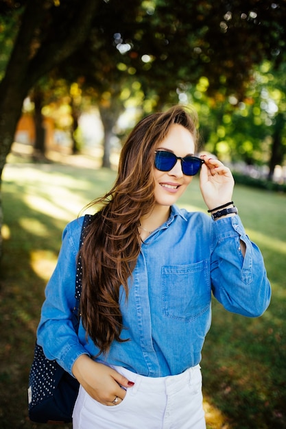 公園の背景に対してサングラスをかけた若い女性の肖像画