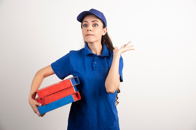 Portrait of young woman in uniform smiling and delivering pizza . High quality photo
