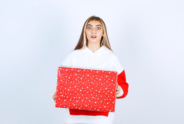 Portrait of young woman in warm hoodie holding Christmas present