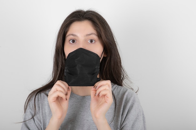 Foto gratuita ritratto di giovane donna che indossa la maschera facciale nera su bianco.