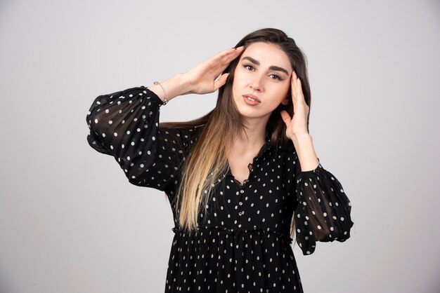 Portrait of young woman wearing dress and touching head .