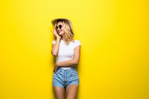 Portrait young woman wearing straw hat posing over colorful yellow wall